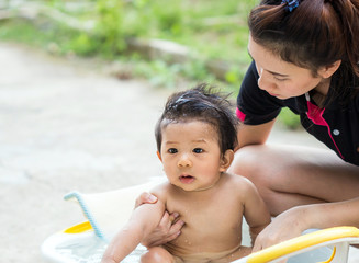 a baby bathing with her mother in the garden.