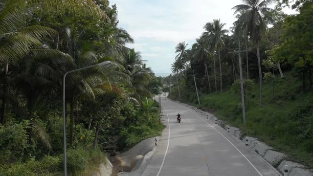 flat aerial shot in cinelike-D. Biker riding motorcycle by the road