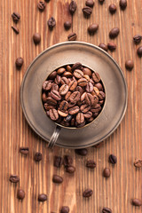 Coffee beans in a silver cup on  wooden  table