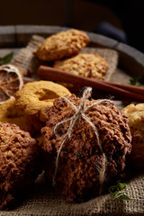 Conceptual composition with assortment of cookies and cinnamon on a wooden barrel, selective focus, close-up
