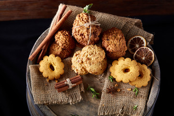Obraz na płótnie Canvas Conceptual composition with assortment of cookies and cinnamon with napkin on a wooden barrel, selective focus