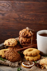 Conceptual festive composition with a cup of hot tea, cookies and spicies on a wooden barrel, selective focus, vertical