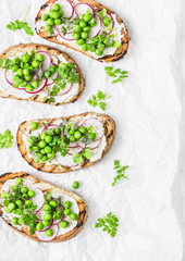 Cream cheese, green peas, radishes and micro greens spring sandwiches on a light background, top view.  Healthy eating, diet concept. Flat lay, free space for text