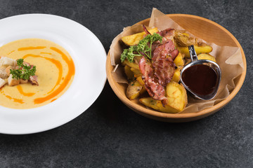 Complex dinner. Fried potatoes with appetizing bacon and sauce are in a wooden plate