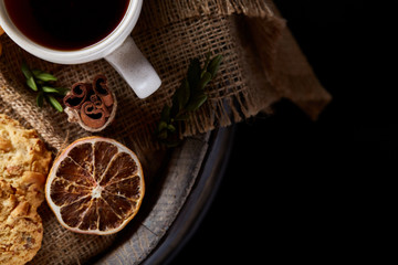 Obraz na płótnie Canvas Conceptual festive composition with a cup of hot tea, cookies and spicies on a wooden barrel, selective focus, close-up