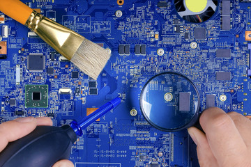 Male hands working on disassembling and cleaning circuit board in laptop using brush. Computer...
