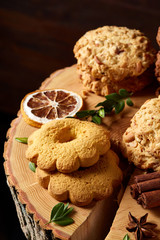 Christmas concept with assortment of cookies and decorations on a log over wooden background, selective focus