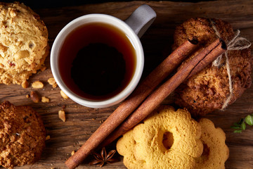 Traditional Christmas tea concept with a cup of hot tea, cookies and decorations on a wooden background, selective focus