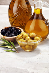 Bottle virgin olive oil and oil in a bowl with some olives