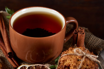 Conceptual festive composition with a cup of hot tea, cookies and spicies on a wooden barrel, selective focus, close-up