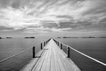 Obrazy na Szkle  Czarno-biały Krajobraz drewniany most w błękitnym morzu na tropikalnej plaży.
