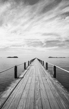 Fototapeta Czarno-biały krajobraz drewnianego mostu w błękitne morze na tropikalnej plaży.