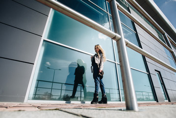 Young spring pretty stylish girl in leather jacket posing, walking outdoors. Fashionable blonde woman with curly long hair