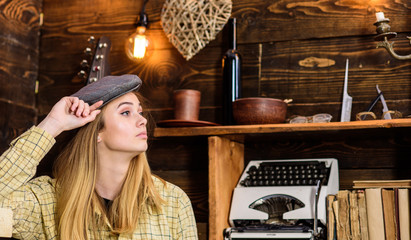Girl in casual outfit with kepi in wooden vintage interior. Tomboy concept. Lady on calm face in plaid clothes looks cute and casual. Girl tomboy spend time in house of gamekeeper