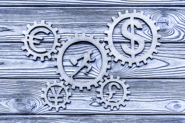 running man with a suitcase, twirled gears, currency signs on a wooden background. business. finance.