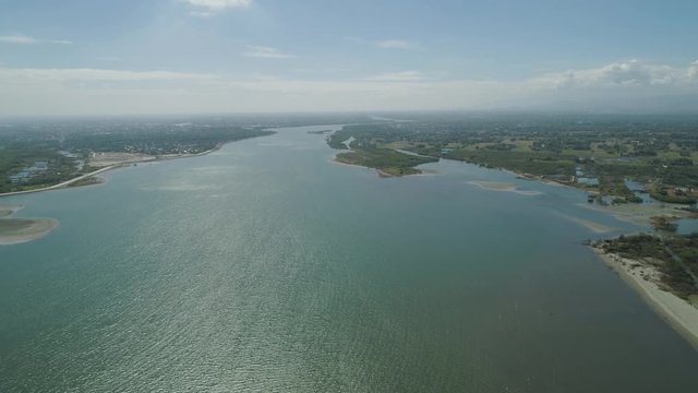 Aerial view of river flowing into the sea on the island Luzon, Philippines. Seascape, ocean and beautiful beach. Panorama of the tropical island.