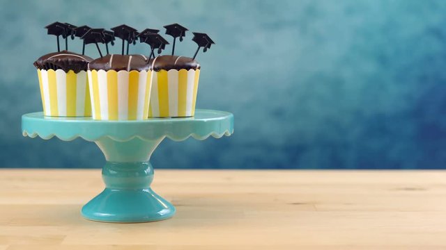 Happy Graduation Day party chocolate cupcakes with graduation cap hat topper decorations in yellow and blue theme.