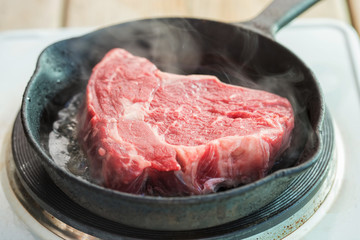 Raw rib eye steak on the frying pan
