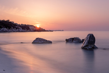 Fototapeta na wymiar Soft Sunrise With Rocks Sun Orange Sky Sardinia Italy