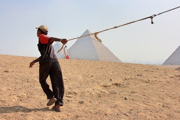 ピラミッドとラクダの手綱を引く少年