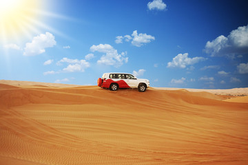 Single SUV car on dessert dunes of Arabian desert in a sunset off-road safari adventure  