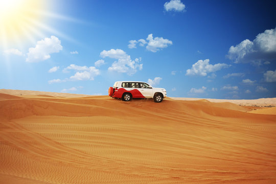 Single SUV car on dessert dunes of Arabian desert in a sunset off-road safari adventure
