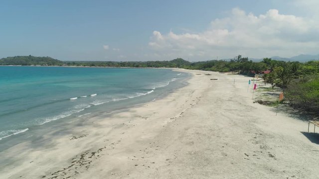 Beautiful tropical beach Cabugao with white sand and palm trees in the Philippines, Luzon. Aerial view of coast with beach and turquoise water.