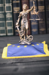 Scales of Justice, Justitia, Lady Justice in front of the European Union flag in the background.