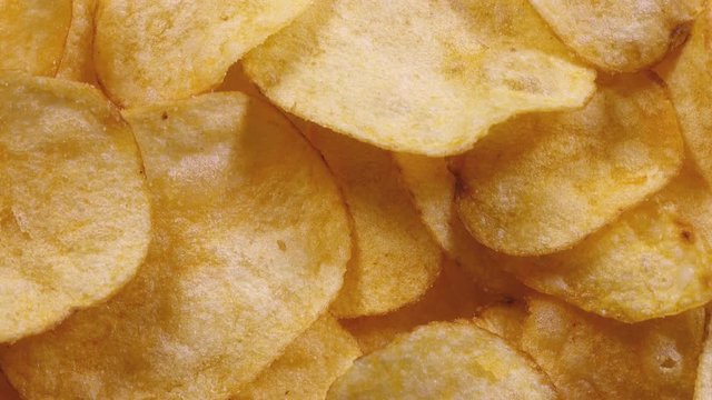 Appetizing potato chips rotating in 4K. Super closeup flat-lay view of popular yummy fast food.
