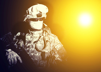Armed infantry with hidden face standing in blinding light of projector or searchlight during...