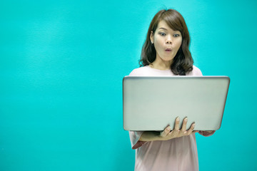 Excited expression woman standing and using laptop with light blue background.copy space image.