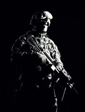 Special operations forces soldier, counter terrorism squad fighter, security service guard, marine shooter in combat uniform, armed with light machine gun low light studio shot on black background