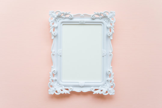 White vintage photo frame on pink pastel wooden background flat lay top view style