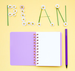 Top view flat lay picture with notepad as mockup for your design with flowers on yellow background.