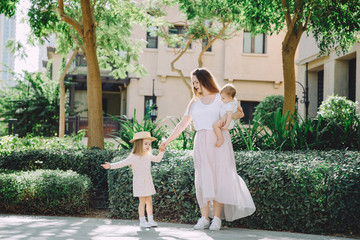 Portrait of happy beautiful mother with her adorable little daughters relaxing in park © TY Studio