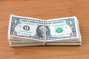 Satck of 1 USD -  United States money with a rubber on the wooden background.