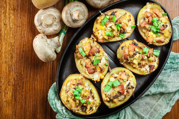 Baked potatoes in jacket stuffed with bacon, mushrooms and chees