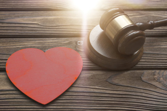 a judge hammer, a wooden heart shape on a wooden background. divorce, conflicts. jurisprudence