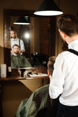 Fototapeta na wymiar Master cuts hair and beard of men in the barbershop