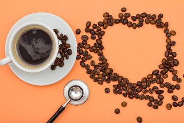 Cup of coffee on saucer with coffee beans folded in the form of a heart and phonendoscope