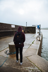 Woman wearing casual clothes standing at harbor in Irish coast