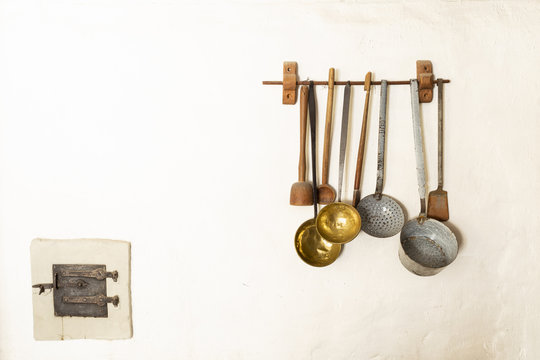 Retro style set of different wooden and metal kitchen spoons and tools hanging on a wall