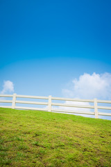 White fence on green field and blue sky - Green environmental concept