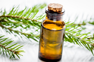 fir branches and spruce aroma oil on white table background