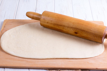 Fresh raw dough and rolling pin