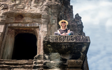 Tourist girl sitting at the temple angkor wat in Cambodia - obrazy, fototapety, plakaty