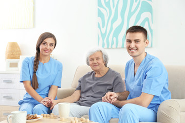 Fototapeta premium Senior woman with young caregivers indoors