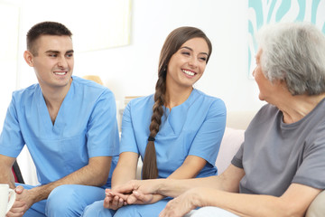 Senior woman with young caregivers indoors
