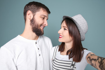 Trendy hipster couple taking selfie against grey background