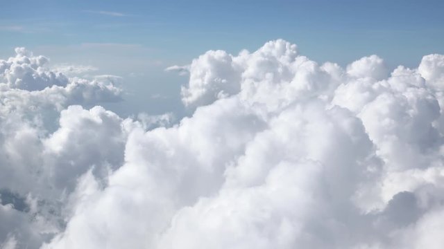 Beautiful cloudy sky. Fluffy сumulus clouds illuminated by sunlight passing by camera. Gorgeous skyscape or cloudscape. Concept of heaven and tranquility. Aerial view from window of flying airplane.